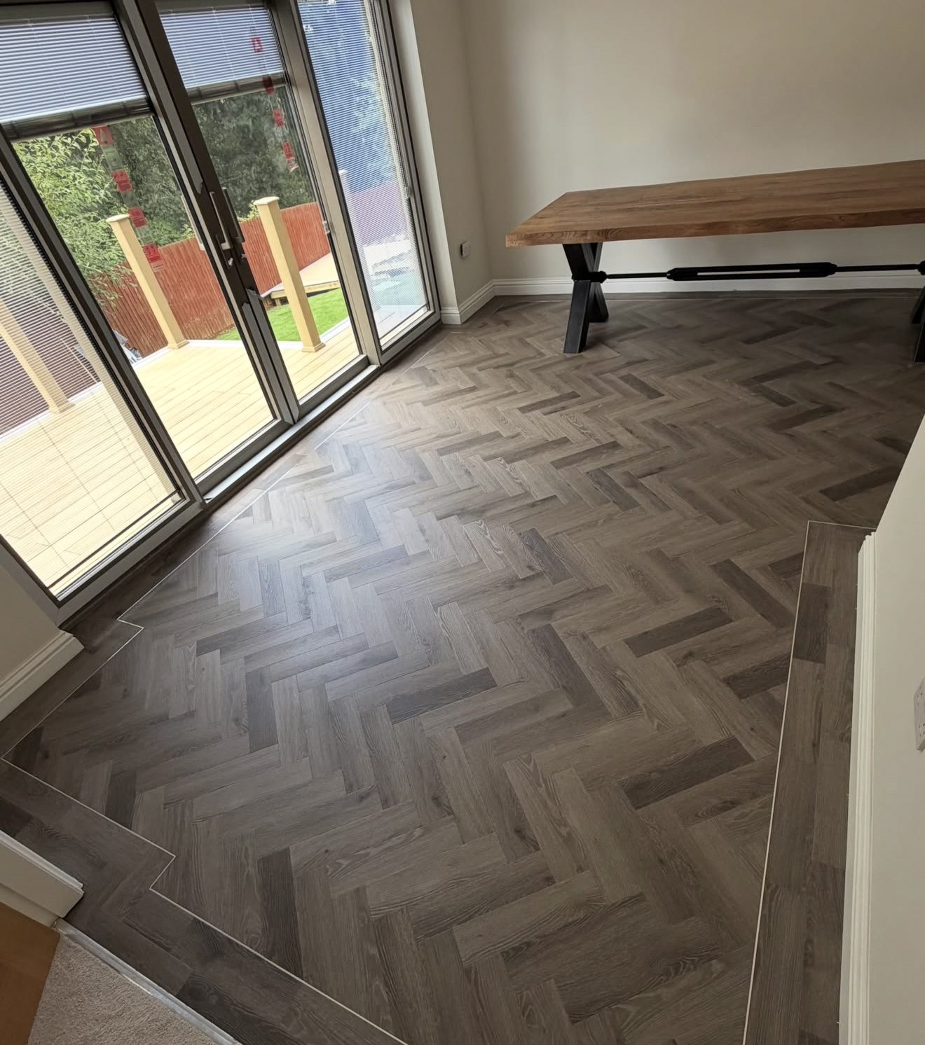 Smoked grey oak herringbone with a perimeter border following the patio doors